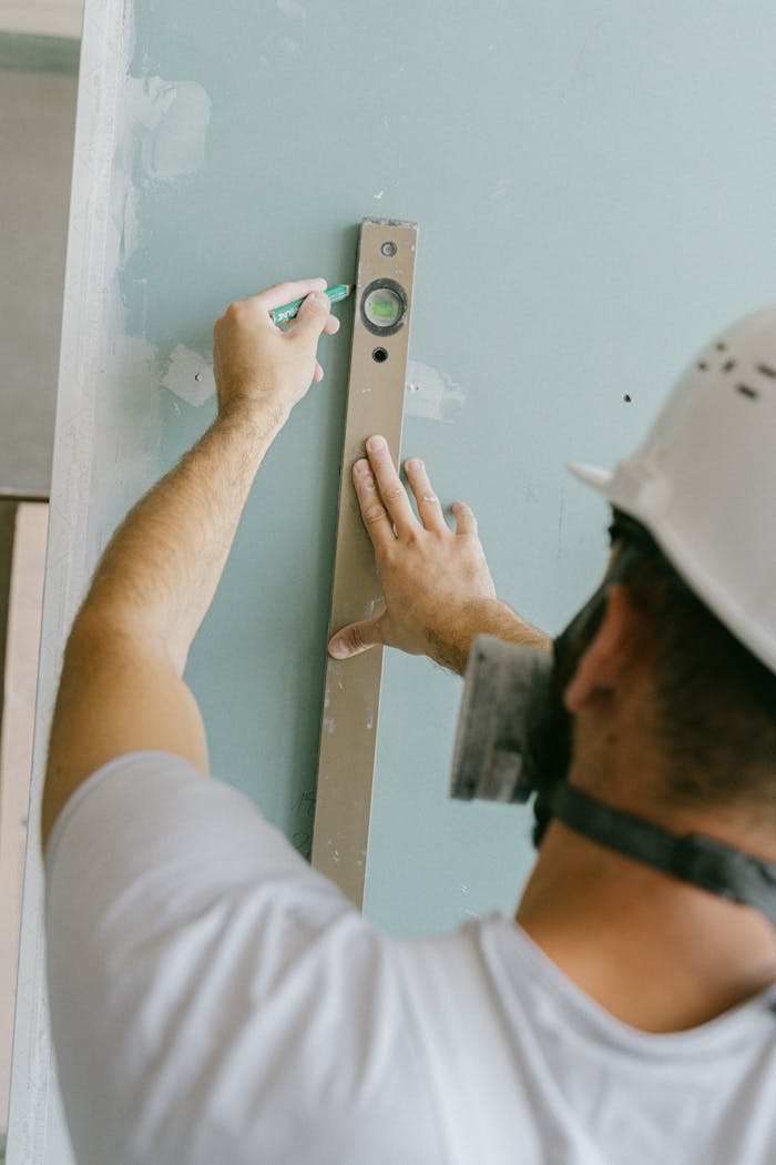 Construction worker measuring a wall with a level for accurate alignment.
